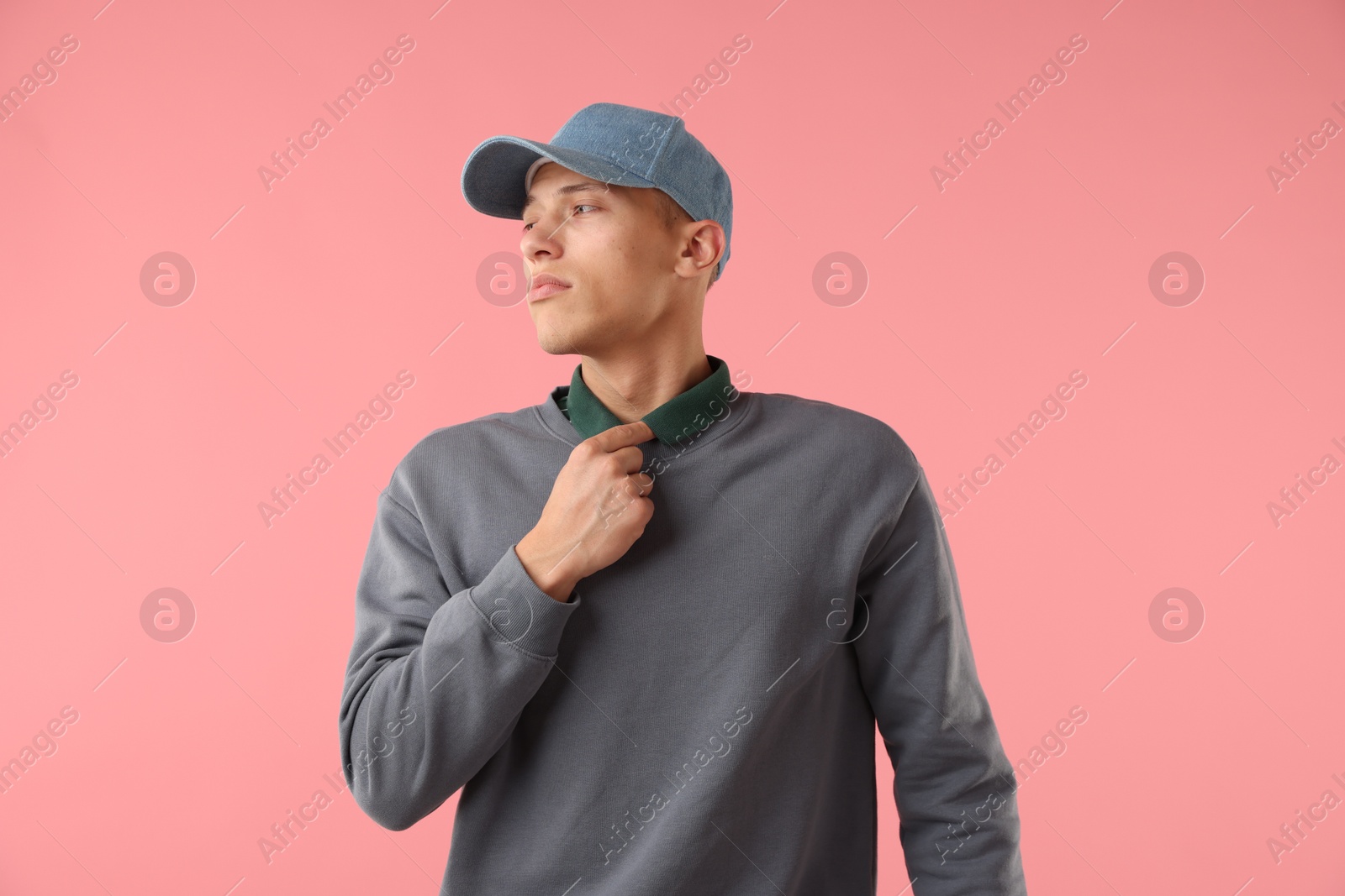 Young man in stylish baseball hat on pink background Photo of Young man in stylish baseball hat on pink background