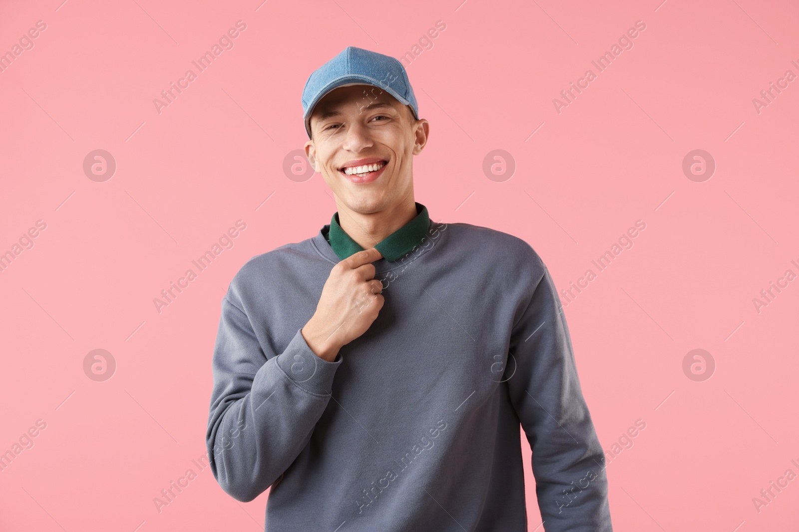 Young man in stylish baseball hat on pink background Photo of Young man in stylish baseball hat on pink background