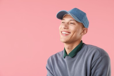 Photo of Young man in stylish baseball hat on pink background, space for text