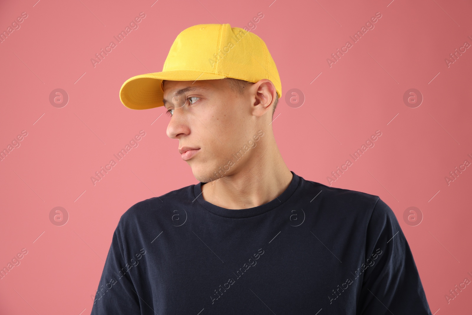 Young man in stylish baseball hat on pink background Photo of Young man in stylish baseball hat on pink background