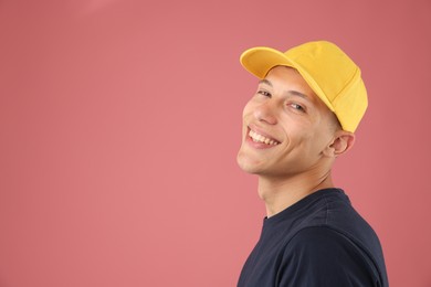Photo of Young man in stylish baseball hat on pink background, space for text
