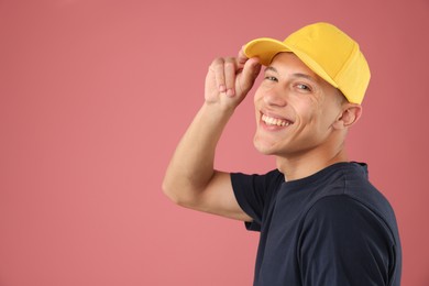 Photo of Young man in stylish baseball hat on pink background, space for text