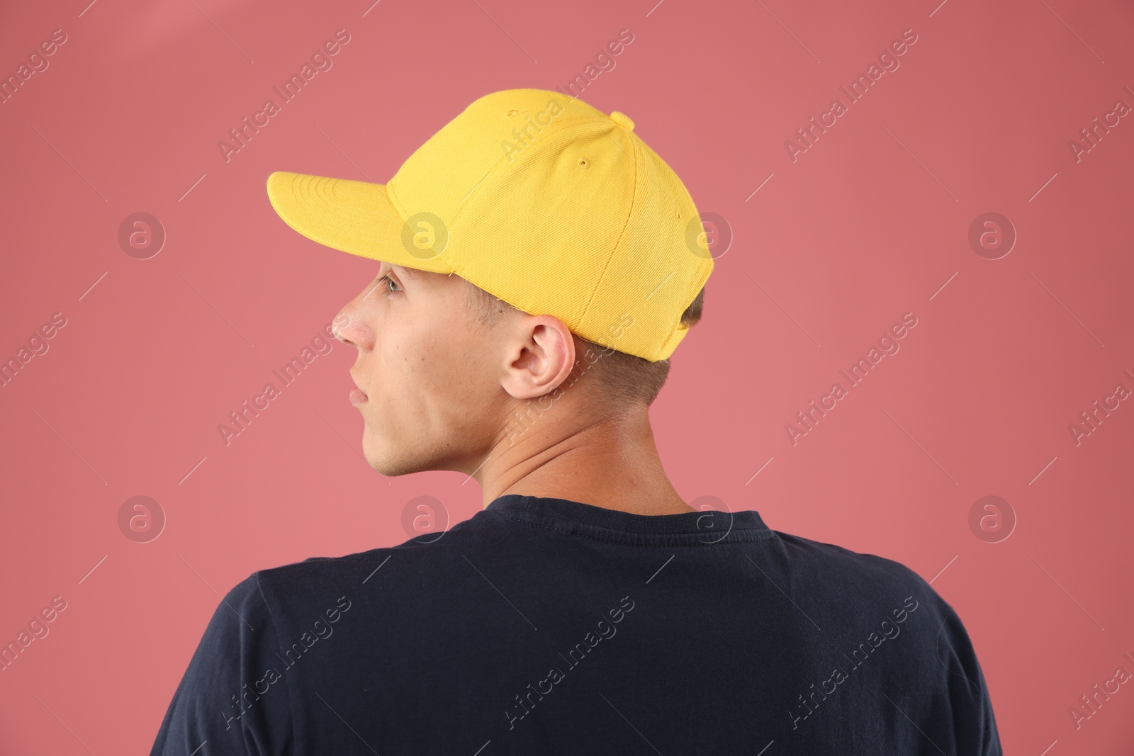 Young man in stylish baseball hat on pink background Photo of Young man in stylish baseball hat on pink background