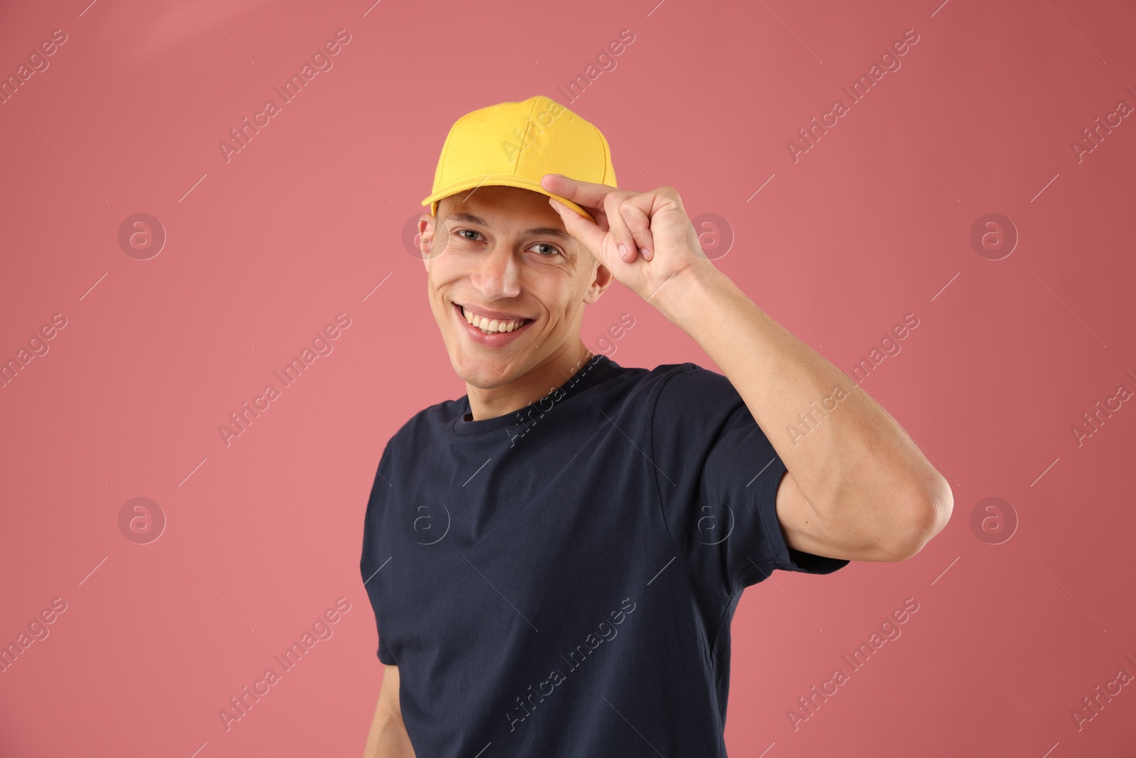 Young man in stylish baseball hat on pink background Photo of Young man in stylish baseball hat on pink background