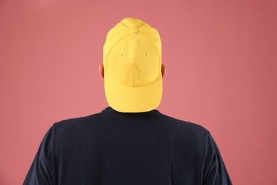 Photo of Young man in stylish baseball hat on pink background, back view