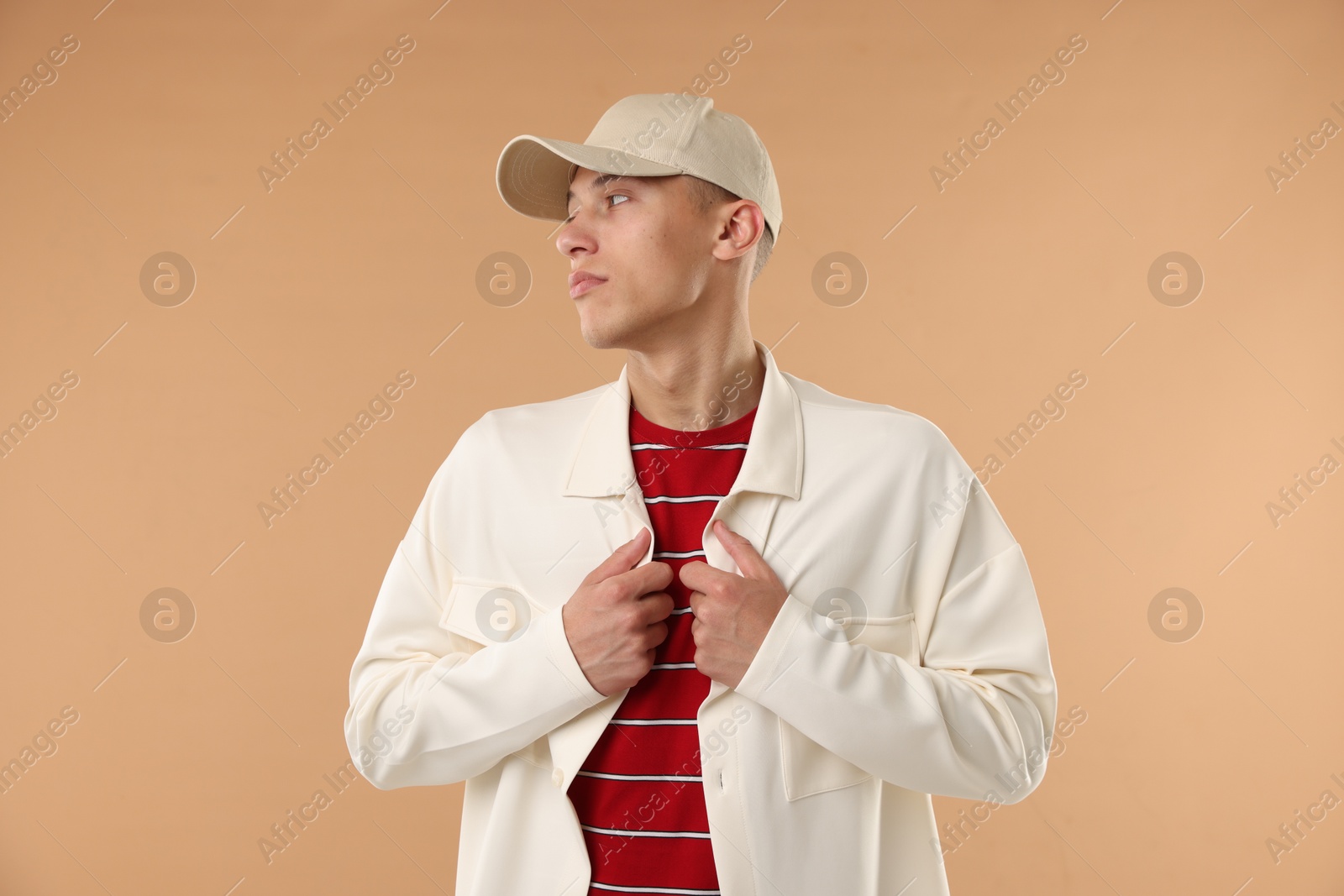 Young man in stylish baseball hat on beige background Photo of Young man in stylish baseball hat on beige background