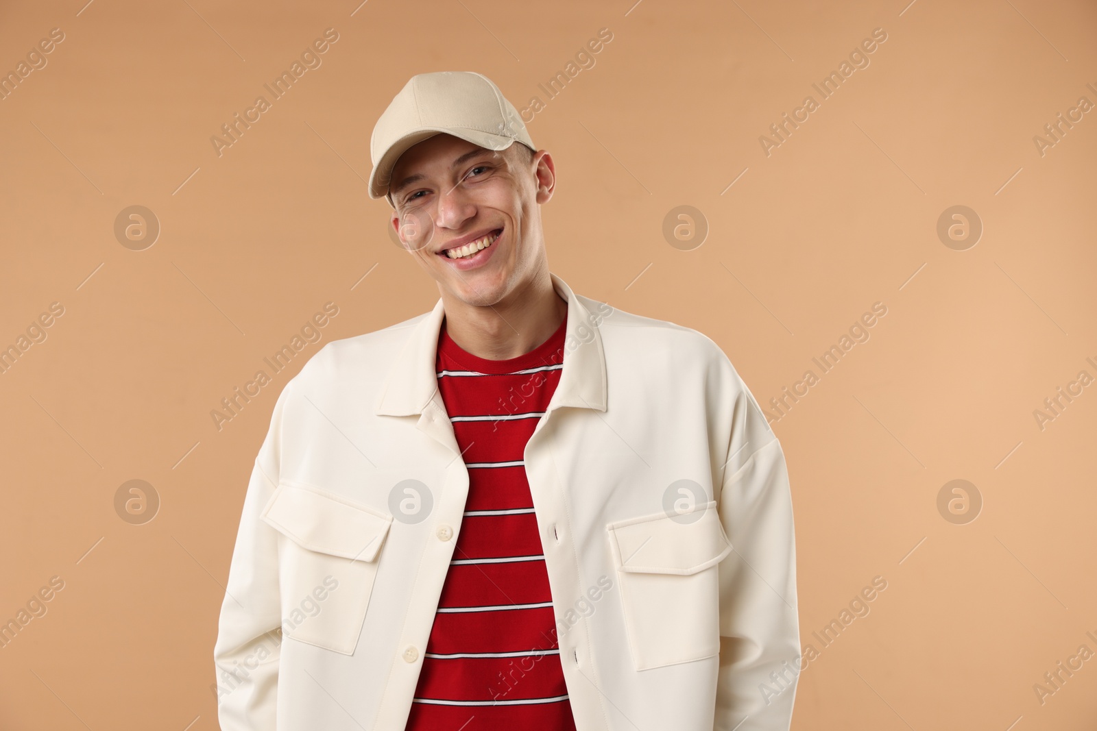 Young man in stylish baseball hat on beige background Photo of Young man in stylish baseball hat on beige background