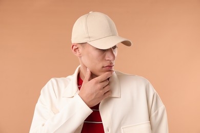 Photo of Young man in stylish baseball hat on beige background