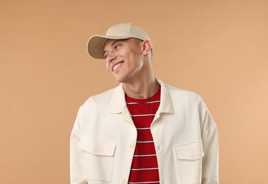 Photo of Young man in stylish baseball hat on beige background