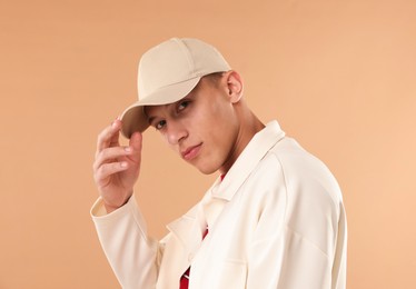 Photo of Young man in stylish baseball hat on beige background