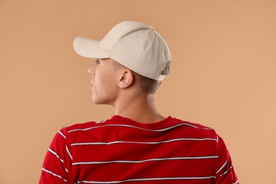 Photo of Young man in stylish baseball hat on beige background