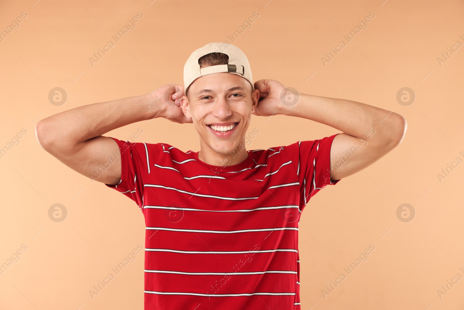 Young man in stylish baseball hat on beige background Photo of Young man in stylish baseball hat on beige background