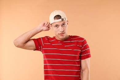 Photo of Young man in stylish baseball hat on beige background