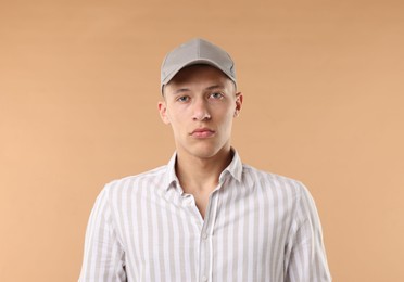 Photo of Young man in stylish baseball hat on beige background