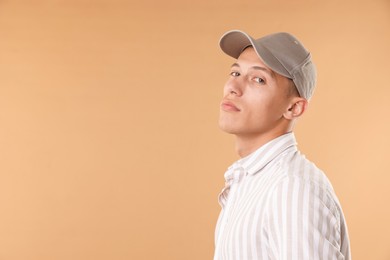 Photo of Young man in stylish baseball hat on beige background, space for text