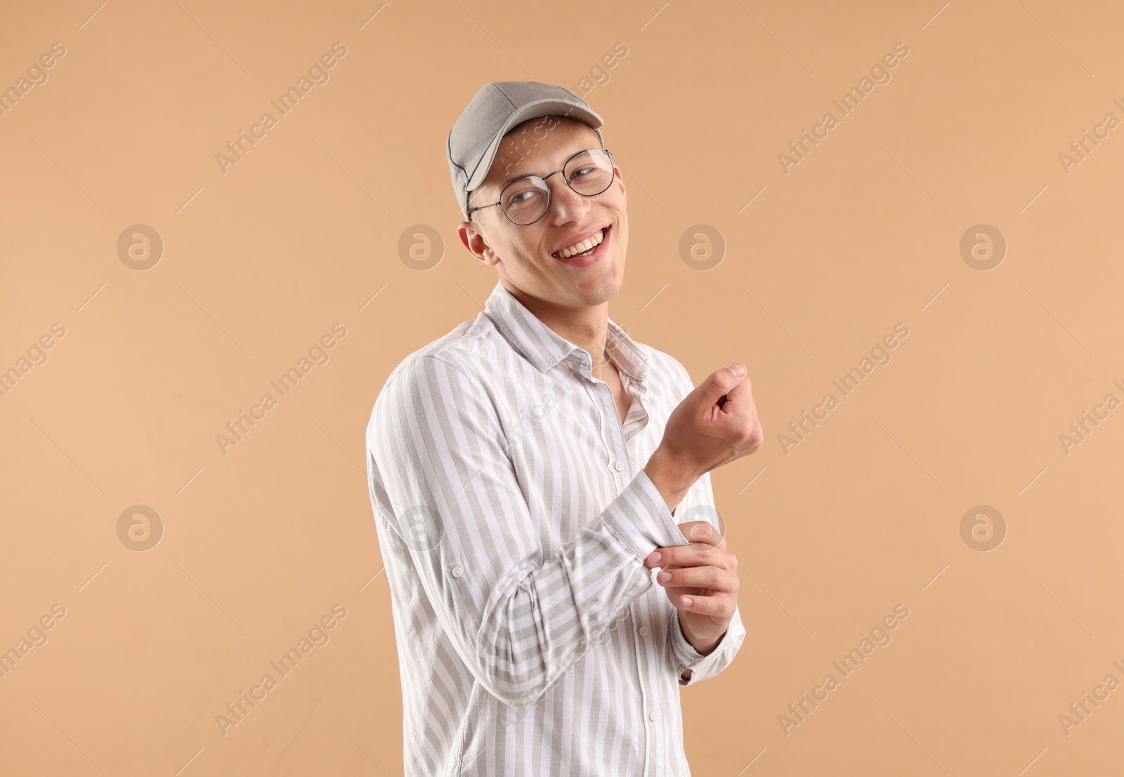 Young man in stylish baseball hat on beige background Photo of Young man in stylish baseball hat on beige background