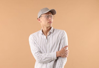 Photo of Young man in stylish baseball hat on beige background