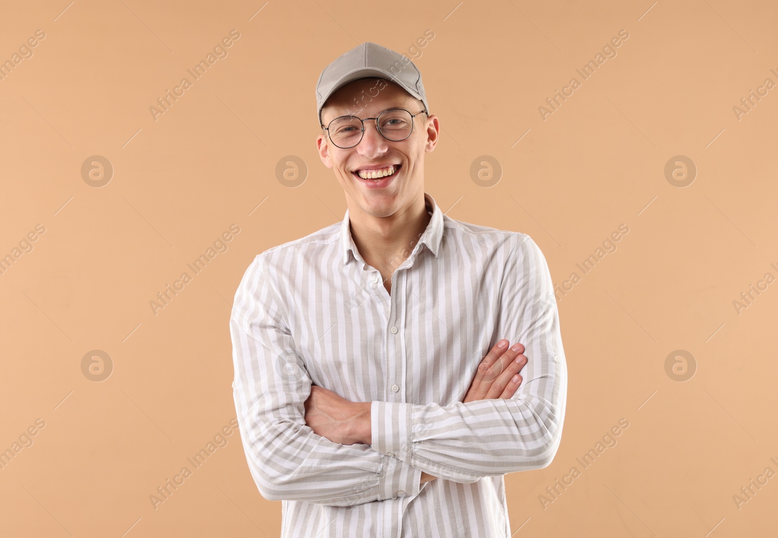 Young man in stylish baseball hat on beige background Photo of Young man in stylish baseball hat on beige background