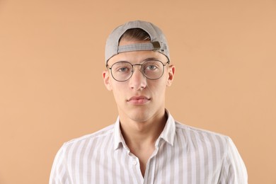 Photo of Young man in stylish baseball hat on beige background