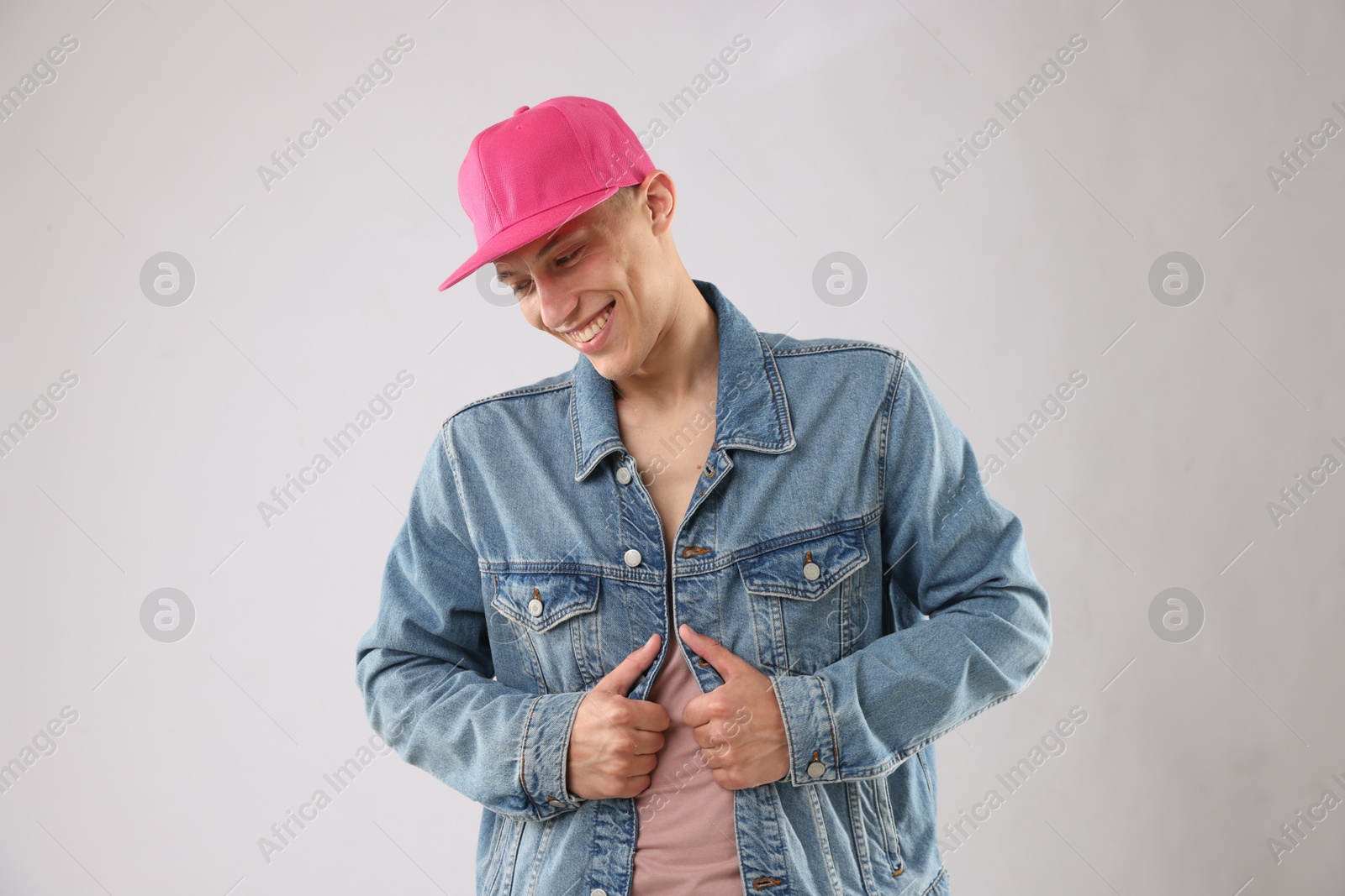 Young man in stylish baseball hat on light grey background Photo of Young man in stylish baseball hat on light grey background