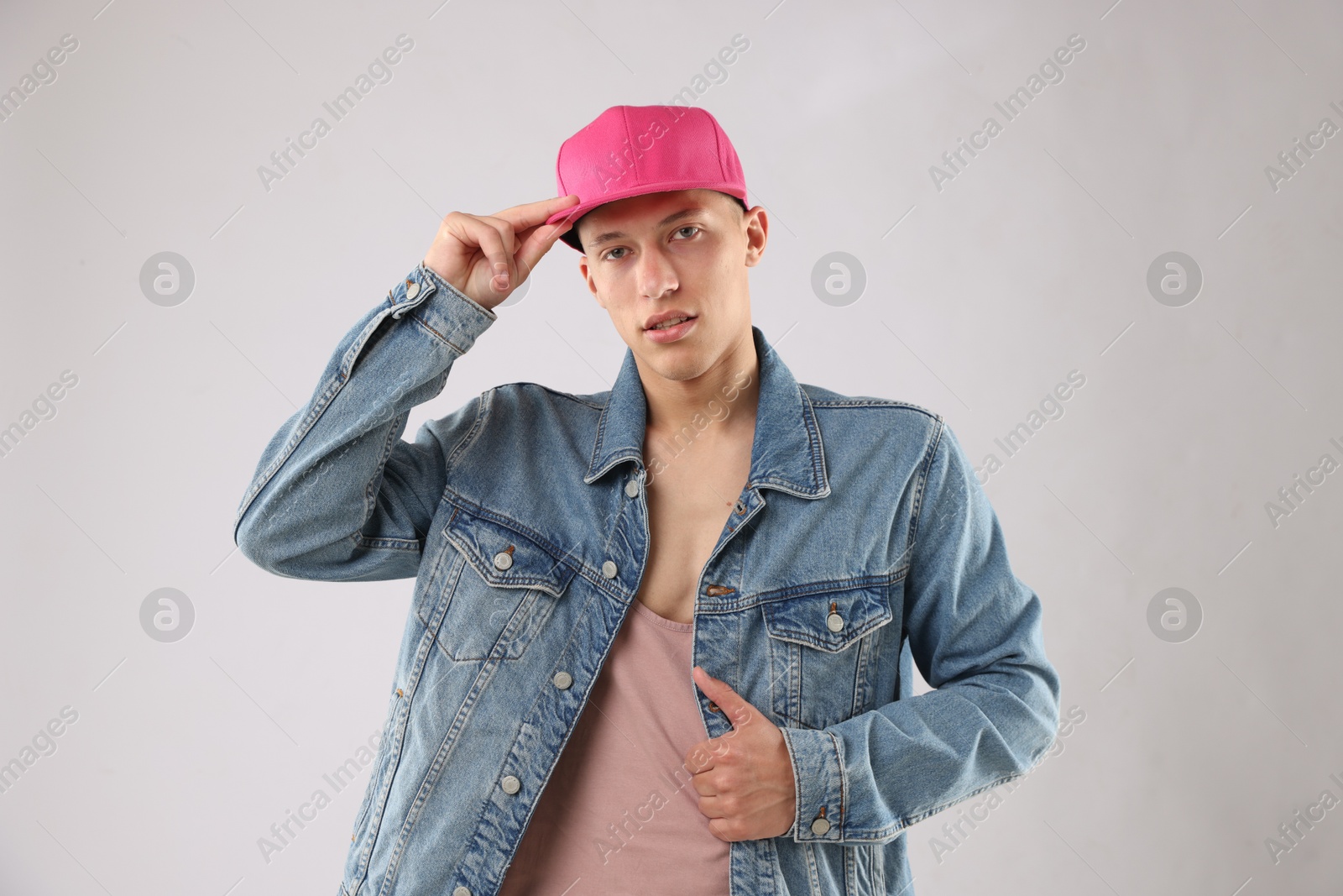 Young man in stylish baseball hat on light grey background Photo of Young man in stylish baseball hat on light grey background
