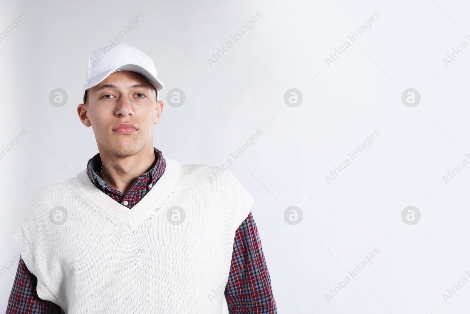 Young man in stylish baseball hat on light grey background, space for text Photo of Young man in stylish baseball hat on light grey background, space for text