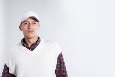 Photo of Young man in stylish baseball hat on light grey background, space for text