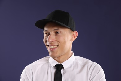 Photo of Young man in stylish baseball hat on dark blue background