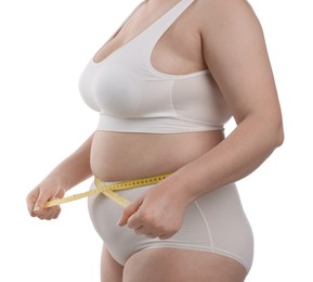 Photo of Weight loss. Plus size woman measuring waist with tape on white background, closeup