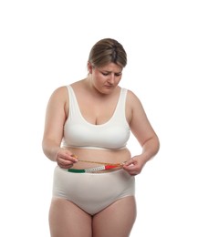 Photo of Weight loss. Plus size woman measuring waist with tape on white background