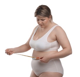 Photo of Weight loss. Plus size woman measuring waist with tape on white background