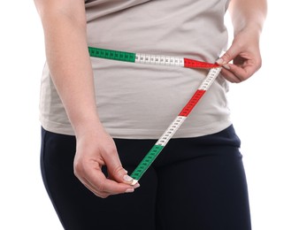 Photo of Weight loss. Plus size woman measuring waist with tape on white background, closeup