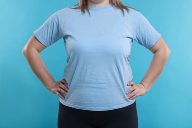 Photo of Weight loss. Plus size woman on light blue background, closeup