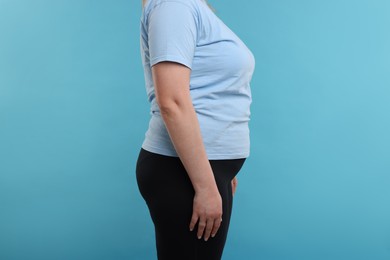 Photo of Weight loss. Plus size woman on light blue background, closeup