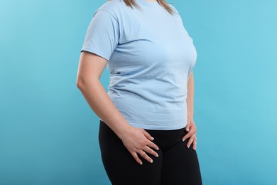 Photo of Weight loss. Plus size woman on light blue background, closeup