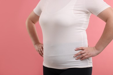 Photo of Weight loss. Plus size woman on pink background, closeup
