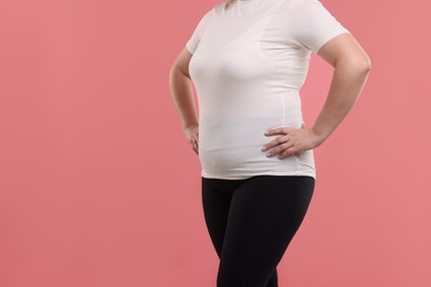 Photo of Weight loss. Plus size woman on pink background, closeup