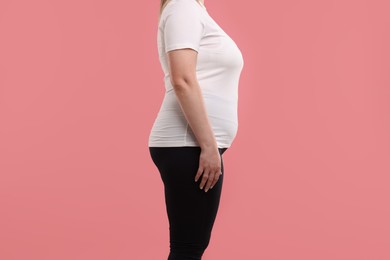 Photo of Weight loss. Plus size woman on pink background, closeup