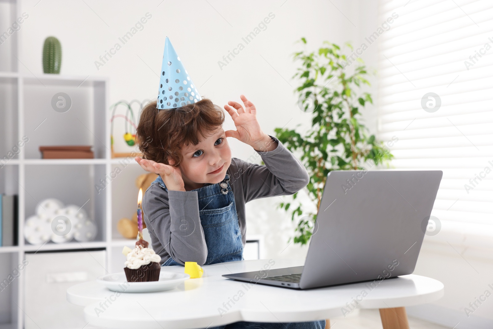 Little boy celebrating his birthday while having video call via laptop at table indoors Photo of Little boy celebrating his birthday while having video call via laptop at table indoors