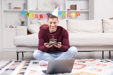 Photo of Man with piece of cake celebrating his birthday and having video call via laptop at home