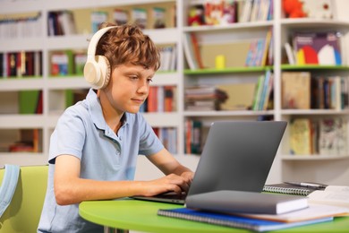 Photo of Student with laptop studying at table in library