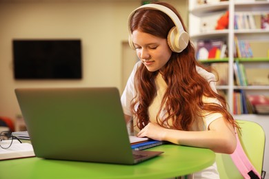 Photo of Student with laptop studying at table in library