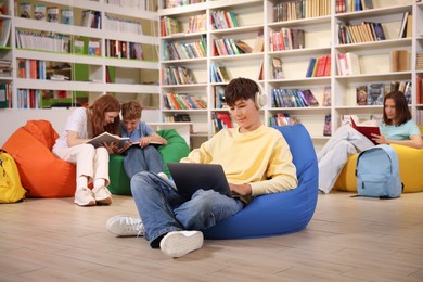 Photo of Student with laptop studying on bean bag in library