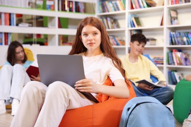 Photo of Student with laptop studying on bean bag in library