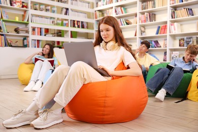 Photo of Student with laptop studying on bean bag in library