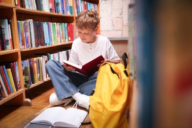 Photo of Student reading book on floor in library