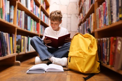 Photo of Student reading book on floor in library