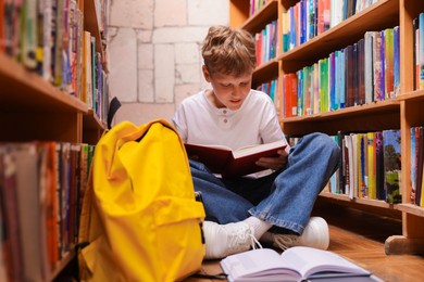 Photo of Student reading book on floor in library