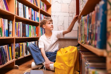 Photo of Student taking book out of shelf in library