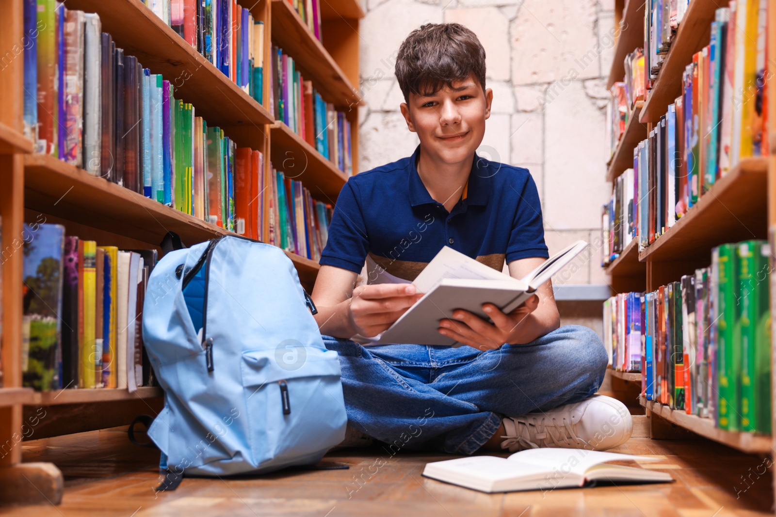 Student with book on floor in library Photo of Student with book on floor in library
